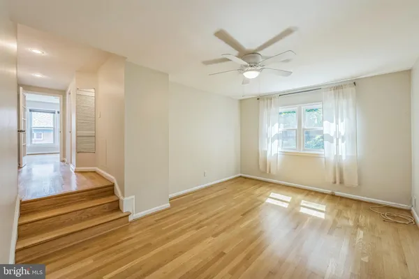 a view of an empty room with window and wooden floor