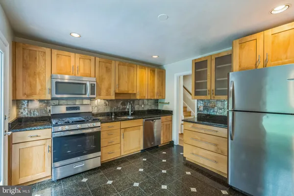 a kitchen with stainless steel appliances granite countertop a refrigerator and a stove top oven