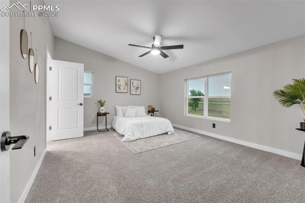 6185 Night Train Lane Yoder, CO 80864 - Photo 14 of 38 a spacious bedroom with a bed and a chandelier