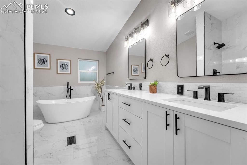 6185 Night Train Lane Yoder, CO 80864 - Photo 17 of 38 a spacious bathroom with a double vanity sink mirror and bathtub