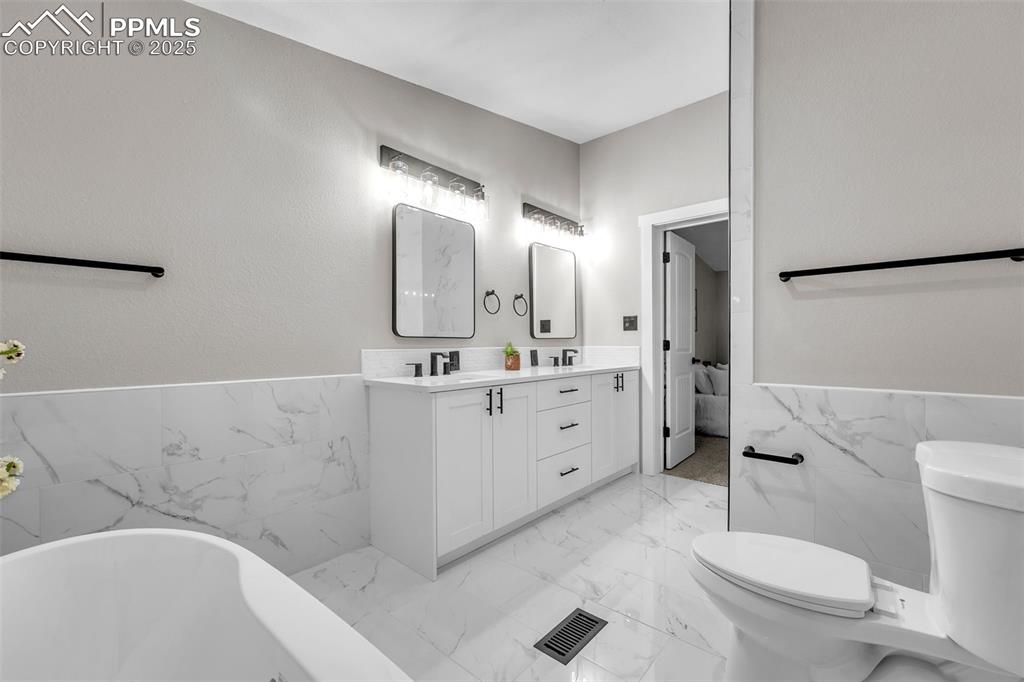 6185 Night Train Lane Yoder, CO 80864 - Photo 18 of 38 a bathroom with a double vanity sink toilet mirror and bathtub