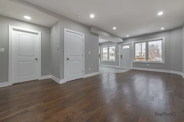 an empty room with wooden floor and windows with curtains