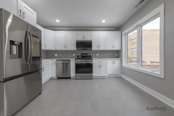a kitchen with stainless steel appliances granite countertop a refrigerator a stove a sink and a microwave