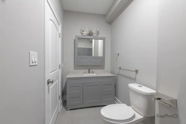 a bathroom with a granite countertop toilet sink and mirror