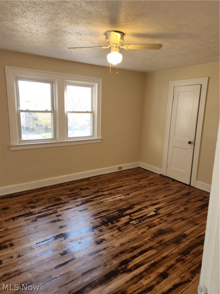 13500 Rugby Road Cleveland, OH 44110 - Photo 12 of 18 Empty room featuring ceiling fan, dark hardwood / wood-style flooring, and a textured ceiling