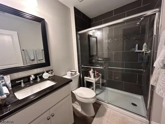 a bathroom with a sink a toilet a mirror and shower