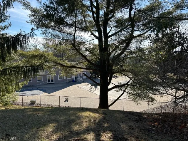 a view of white house with a big yard and large tree