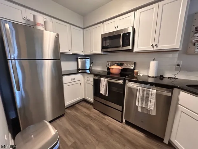 a kitchen with stainless steel appliances granite countertop a refrigerator a stove a sink and a microwave