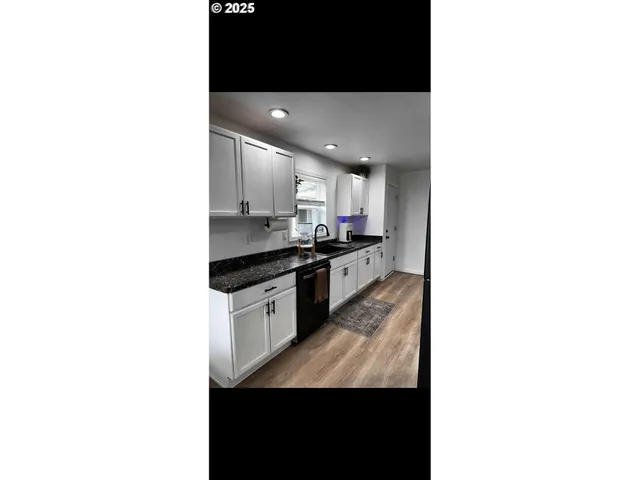 a kitchen with granite countertop white cabinets and black appliances