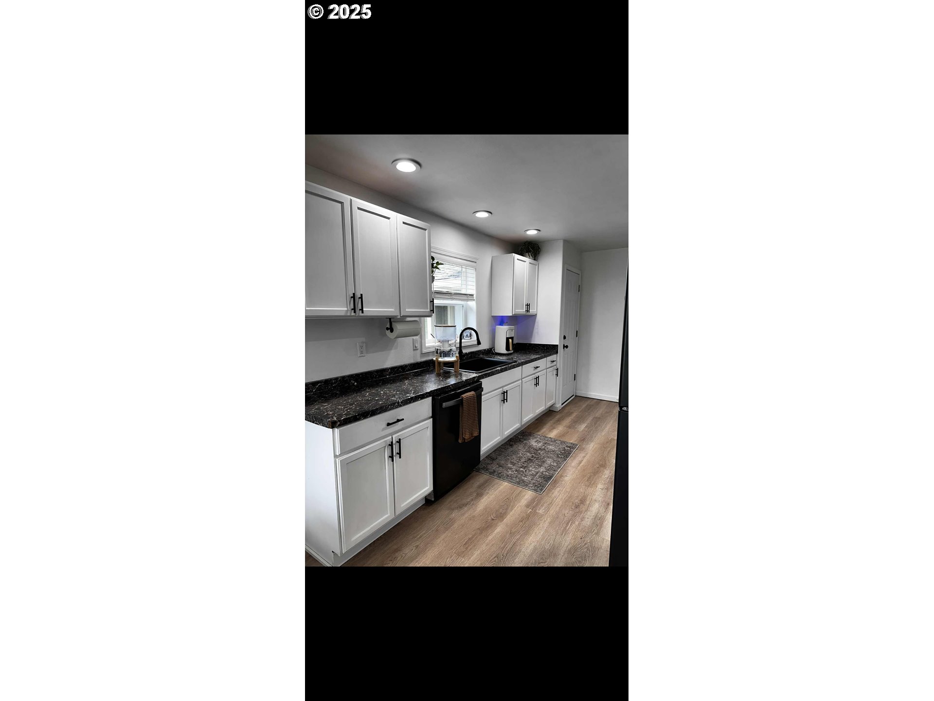 2136 Greenwood Avenue Reedsport, OR 97467 - Photo 16 of 20 a kitchen with granite countertop white cabinets and black appliances
