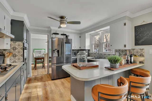 a kitchen with a refrigerator a sink a stove and chairs