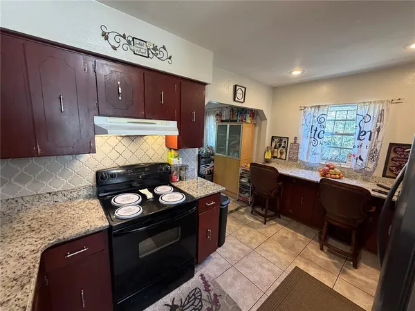 a kitchen with granite countertop stove top oven microwave and cabinets
