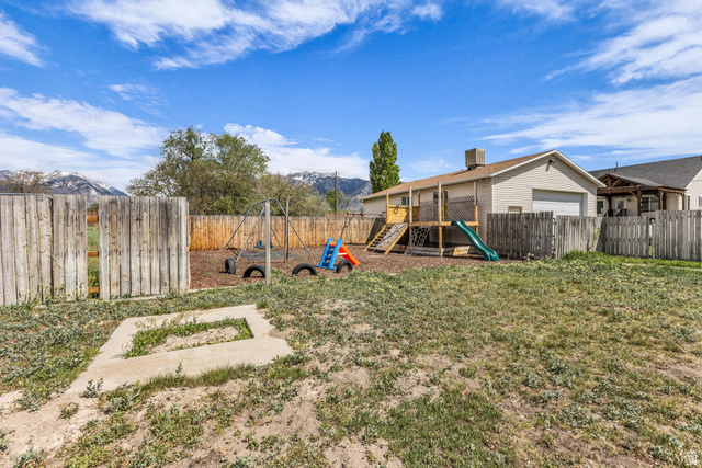 10705 Green Ridge Drive Sandy, UT 84070 - Photo 49 of 55 Fenced backyard featuring a playground, a mountain view, and a garage