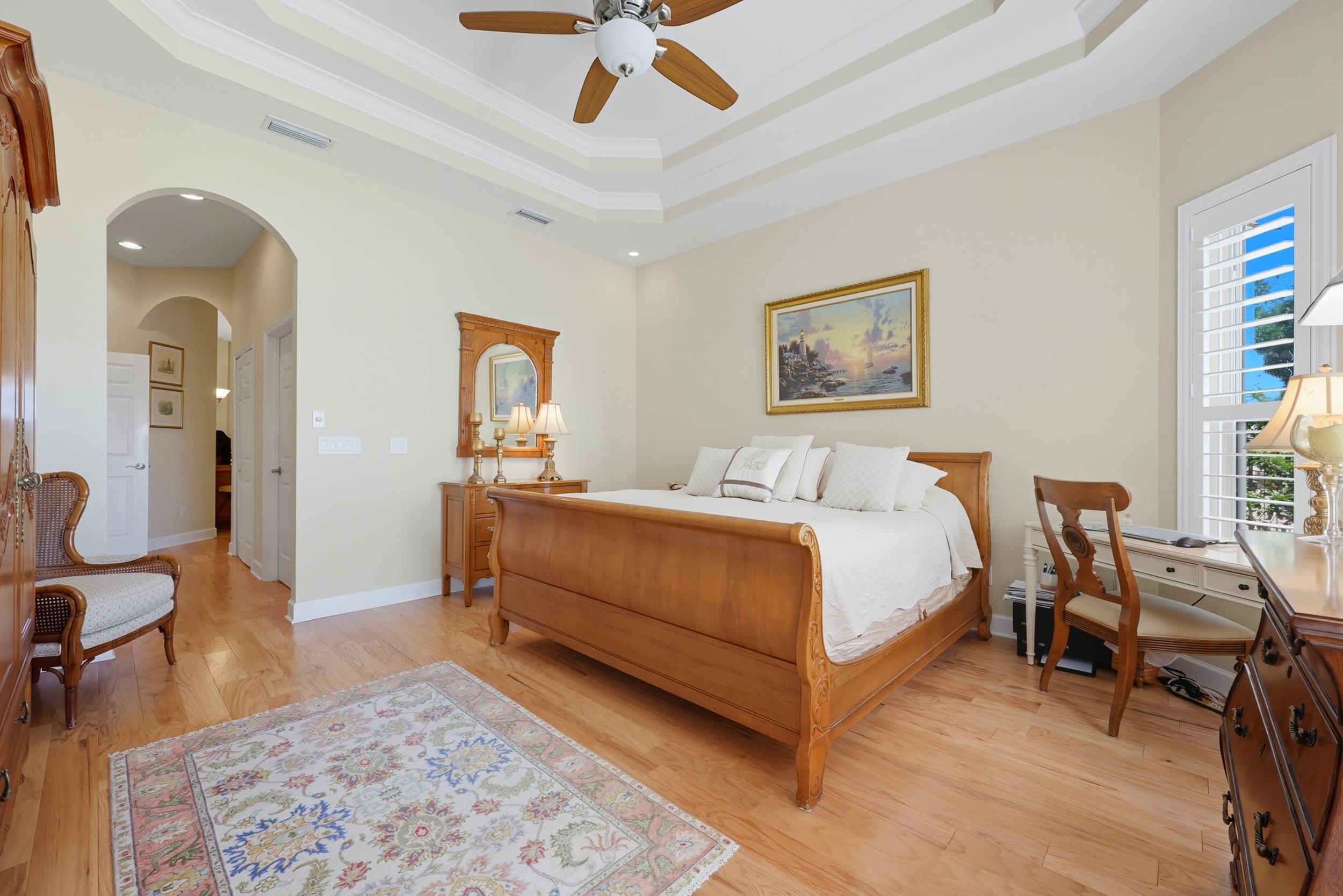 305 Marsh Point Circle St. Augustine, FL 32080 - Photo 24 of 82 Bedroom with arched walkways, light wood-style floors, ceiling fan, a tray ceiling, and crown molding
