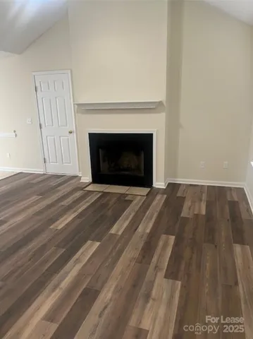 a view of empty room with wooden floor fireplace
