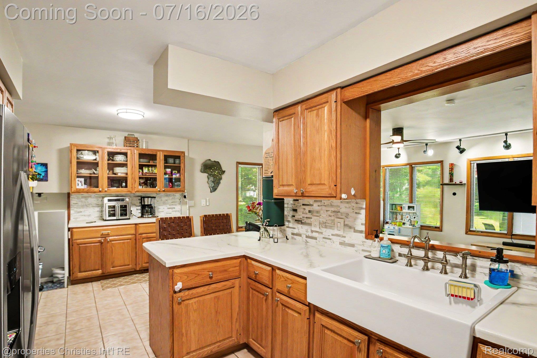 3304 Riverside Drive Port Huron, MI 48060 - Photo 7 of 26 Kitchen featuring a white farmhouse sink, light wood cabinetry, white quartz-finish countertops, a mosaic tile backsplash, and tile flooring