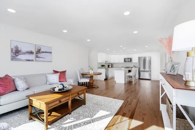 a living room with furniture a wooden floor and kitchen view