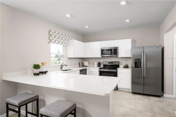 a kitchen with stainless steel appliances a refrigerator a sink a stove a microwave a dining table and chairs