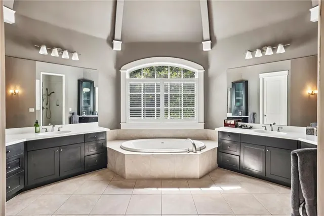 a large spacious bathroom with a tub a double vanity sink a window and mirror
