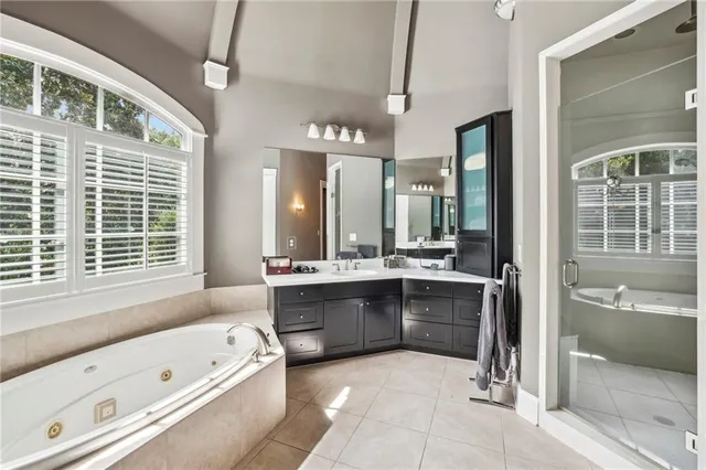 a bathroom with a tub a double vanity sink and large mirror