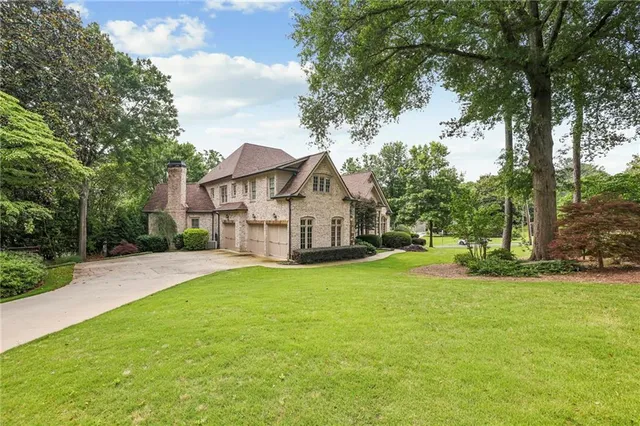 a view of a house with a yard and large trees