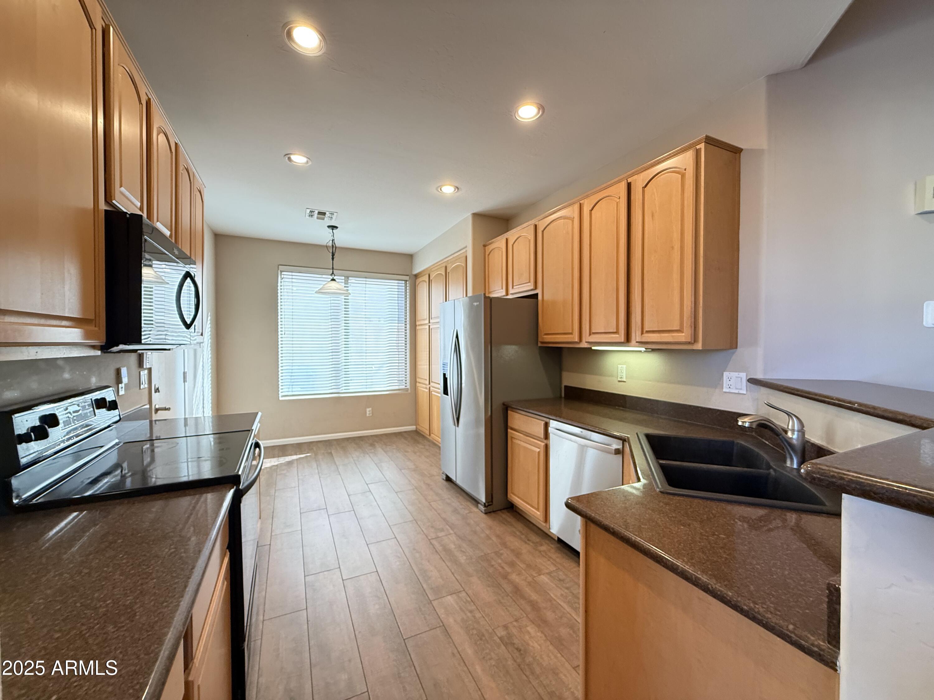 4805 East Wagoner Road Scottsdale, AZ 85254 - Photo 2 of 12 a kitchen with stainless steel appliances granite countertop a refrigerator a sink dishwasher a stove and white countertops with wooden floor