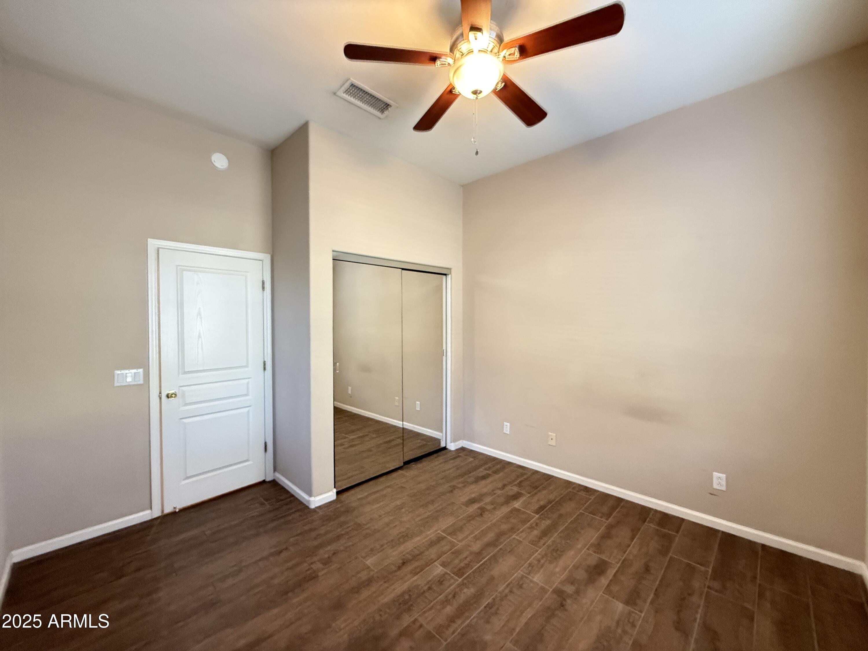 4805 East Wagoner Road Scottsdale, AZ 85254 - Photo 8 of 12 an empty room with wooden floor a ceiling fan and a window