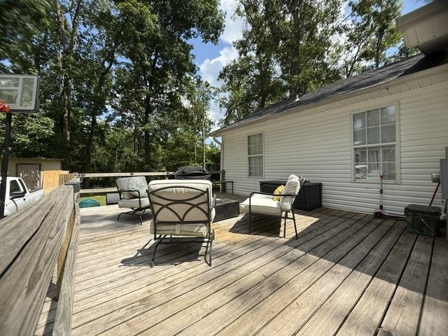 395 Austin Street Savannah, TN 38372 - Photo 30 of 32 Expansive wooden deck with railing, offering multiple seating areas, set against a backdrop of mature trees
