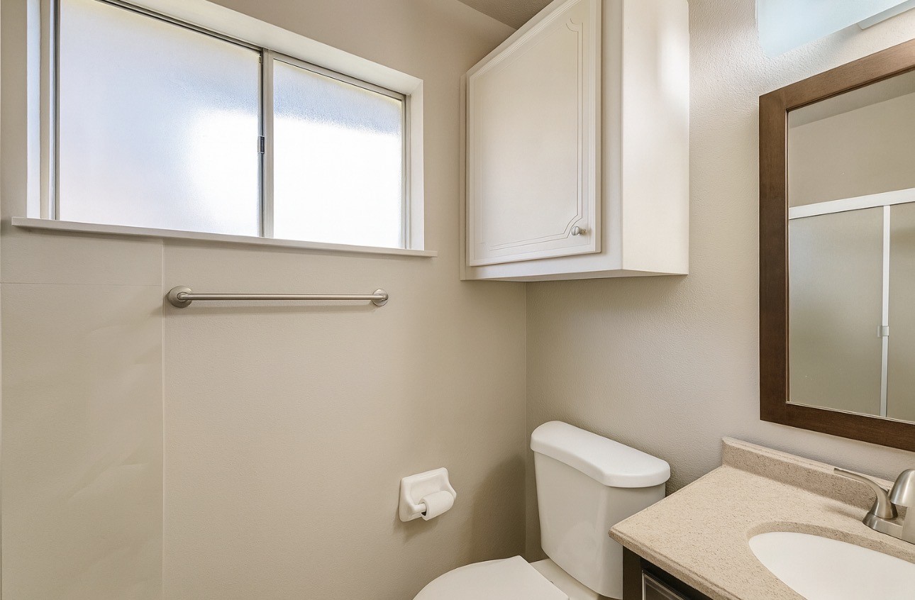 9811 Mango Street Houston, TX 77075 - Photo 11 of 14 a bathroom with a toilet a sink and mirror