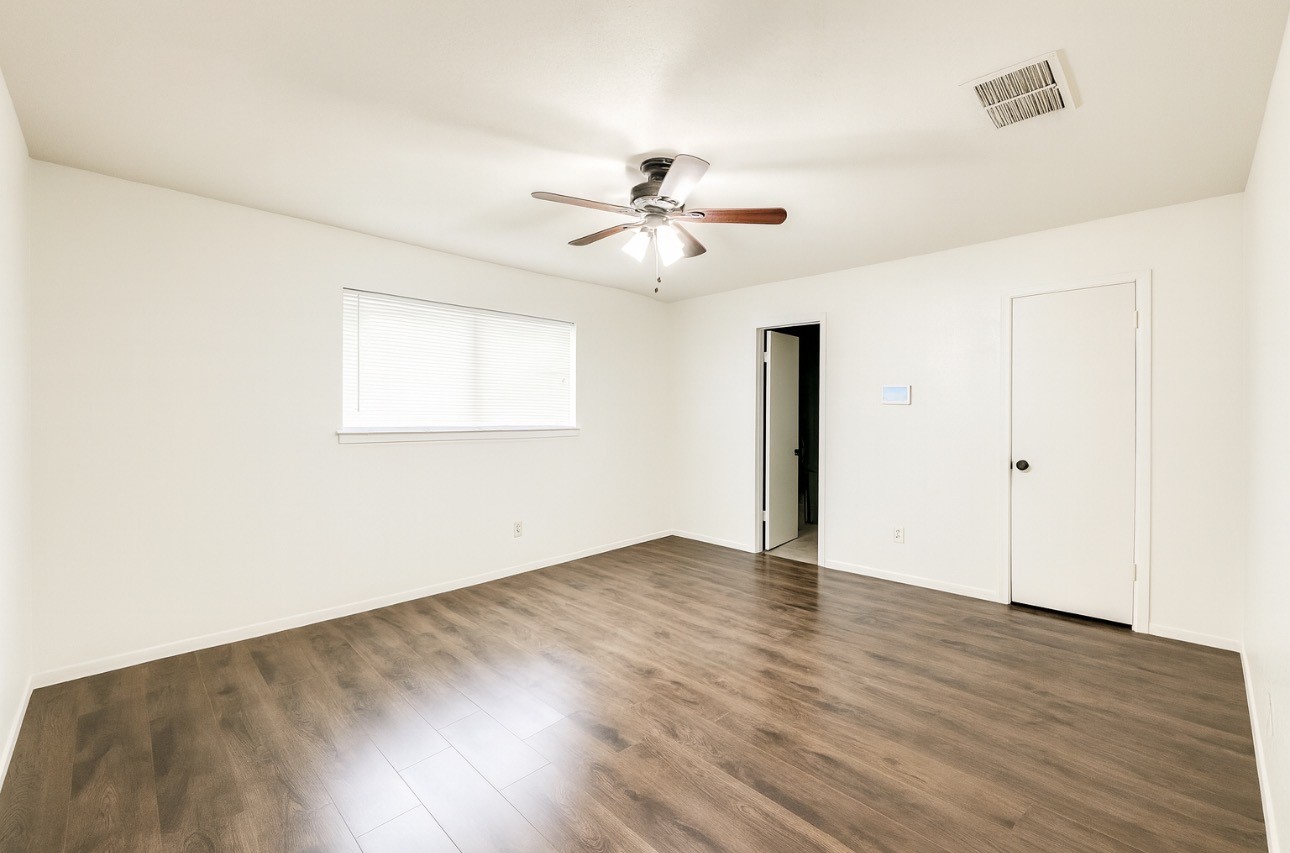 9811 Mango Street Houston, TX 77075 - Photo 8 of 14 an empty room with wooden floor ceiling fan and windows