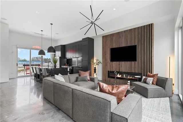 a living room with furniture a flat screen tv and kitchen view