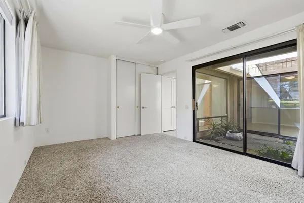 a view of a big room with windows and chandelier fan