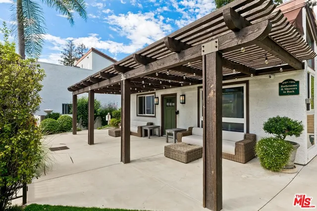 a view of a patio with table and chairs potted plants and floor to ceiling window