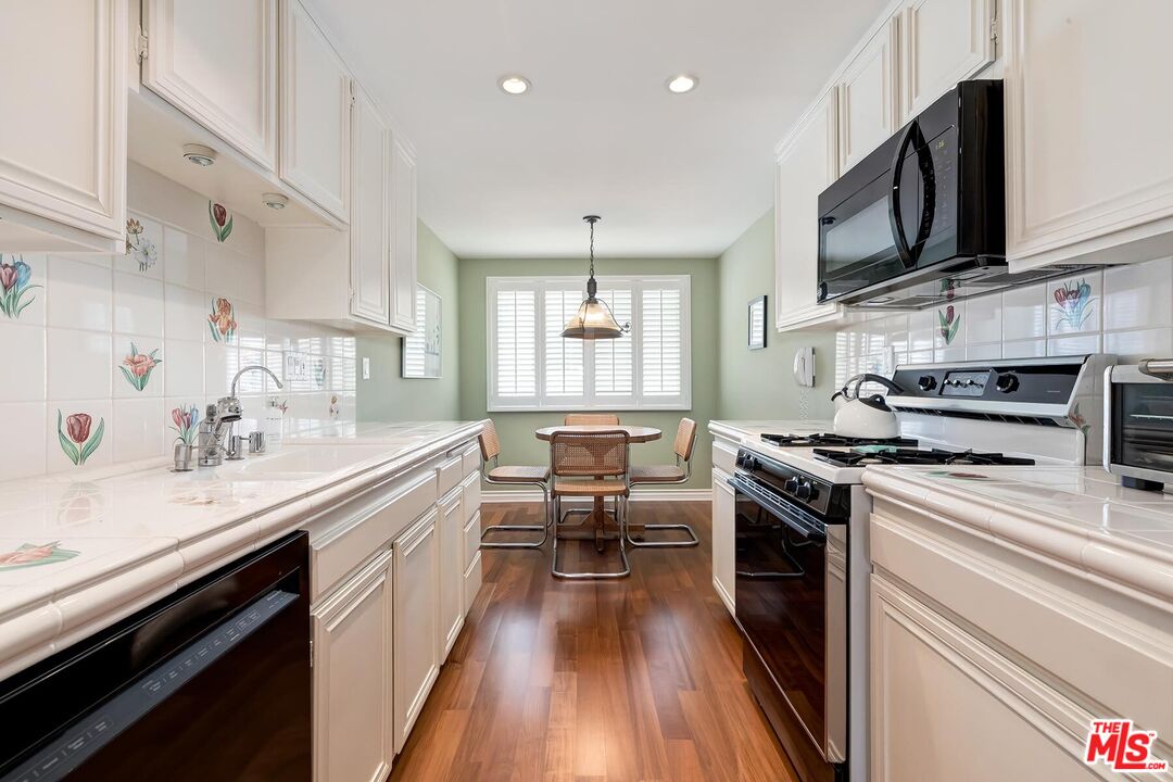 17171 Palisades Circle Pacific Palisades, CA 90272 - Photo 4 of 29 a kitchen with stainless steel appliances a sink wooden floor and a stove top oven