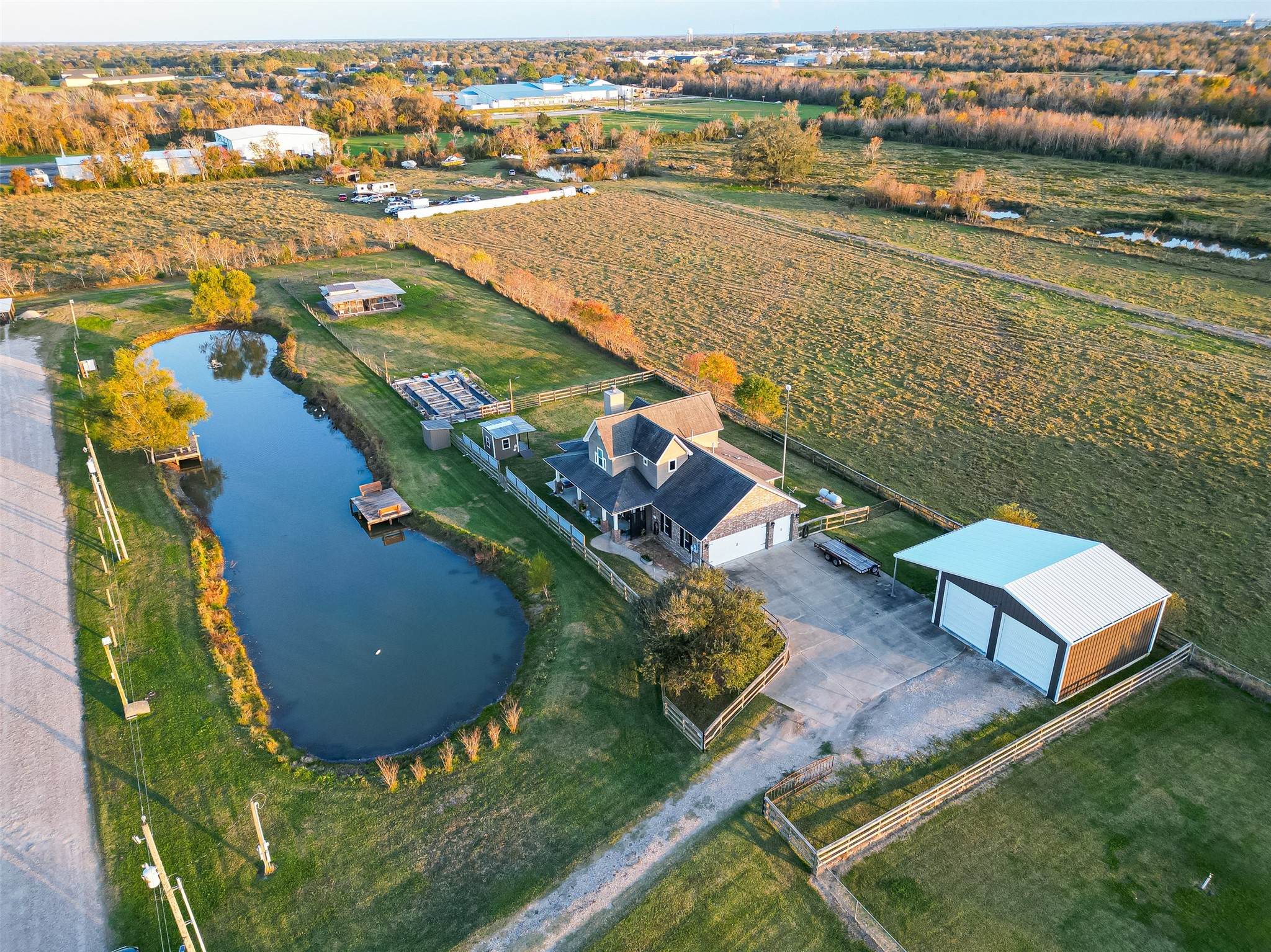 912 County Road 340 Angleton, TX 77515 - Photo 49 of 50 This aerial view showcases a charming country home with a spacious yard and a private pond. The property includes a large garage and a separate outbuilding, perfect for storage or a workshop. Surrounded by open fields, it offers a serene and picturesque setting with ample outdoor space for recreation and relaxation.