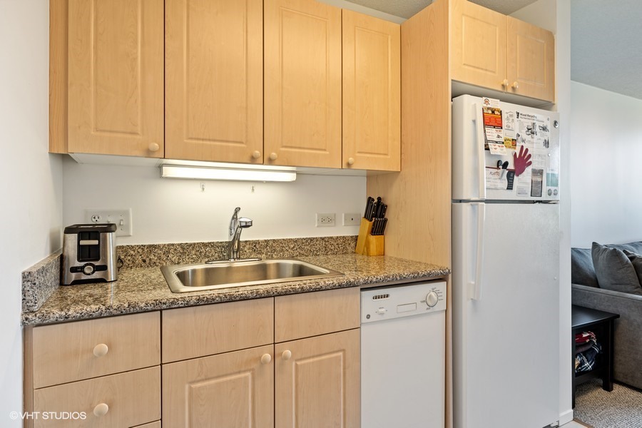 800 Elgin Road, Unit 604 Evanston, IL 60201 - Photo 8 of 17 a kitchen with granite countertop a sink a refrigerator and cabinets