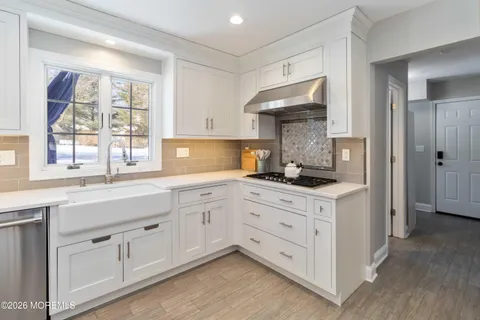a kitchen with white cabinets and window