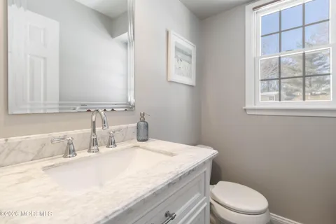 a bathroom with a granite countertop toilet sink and mirror