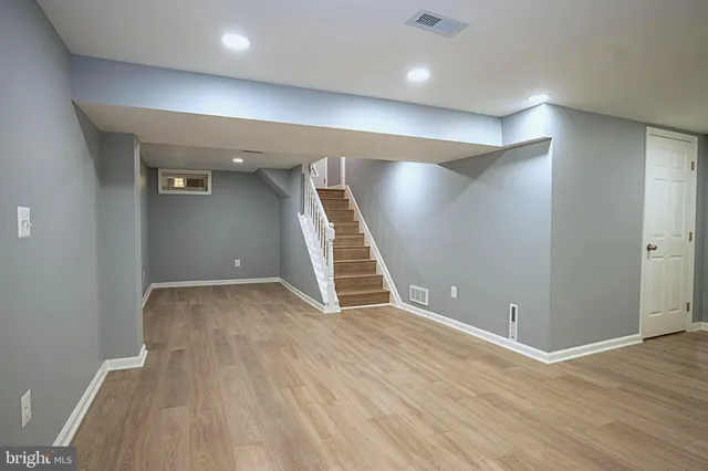an empty room with wooden floor and staircase