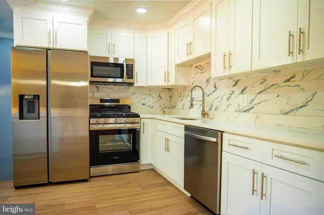 a kitchen with granite countertop white cabinets and stainless steel appliances