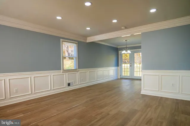 a view of an empty room with window and wooden floor