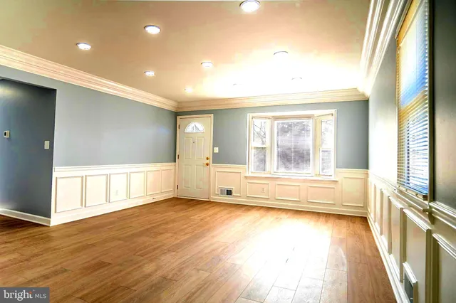 a view of an empty room with a window and wooden floor