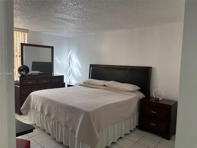 a bedroom with a bed and a lamp on dresser