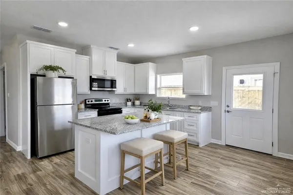 a kitchen with stainless steel appliances granite countertop a refrigerator a stove top oven a sink and cabinets