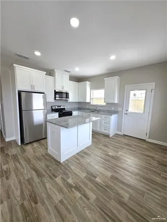a large kitchen with stainless steel appliances granite countertop a stove a sink and a refrigerator