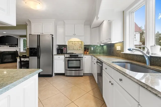 a kitchen with stainless steel appliances granite countertop a sink a stove a refrigerator cabinets and a kitchen island