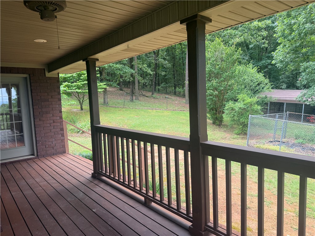 684 Private 2479 Road Clarksville, AR 72830 - Photo 22 of 25 Expansive covered porch featuring wood-finish decking, dark brown railings, and a ceiling fan