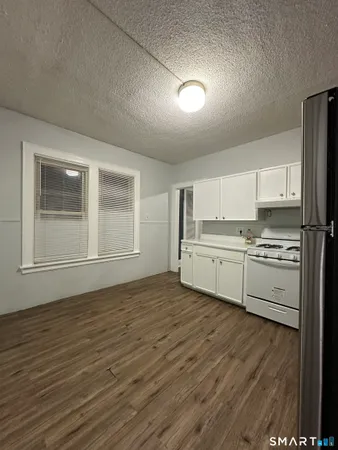 a kitchen with granite countertop a stove cabinets and wooden floor