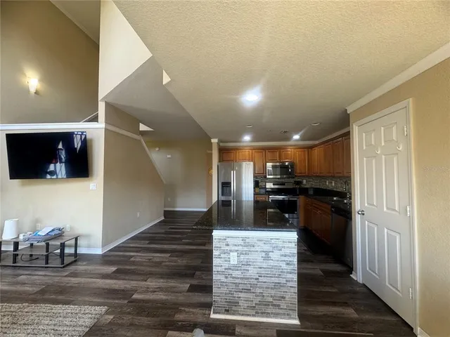a kitchen with stainless steel appliances kitchen island granite countertop a refrigerator and a sink
