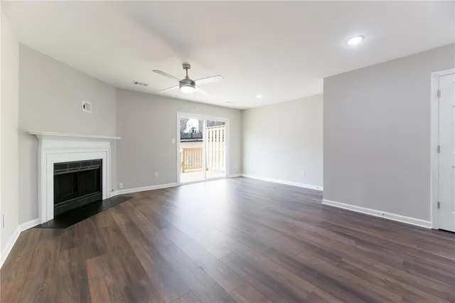 a view of an empty room with wooden floor fireplace and a window
